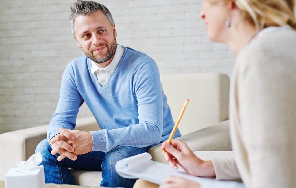 An adult man sitting and talking to a female psychiatrist