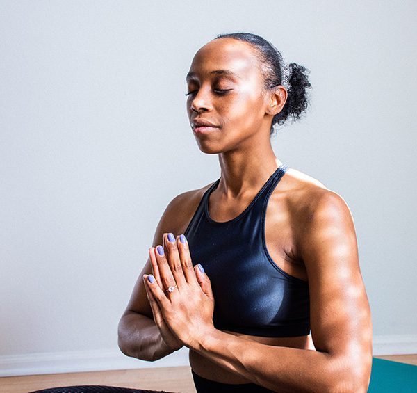 A woman meditating in a brightly-lit yoga studio
