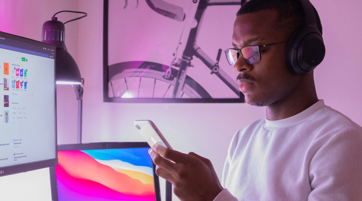 A young Black male looking at his phone while working