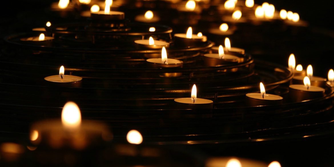 A group of lit tea candles at a memorial service
